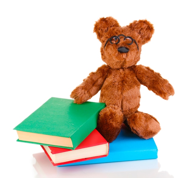 Orso seduto giocattolo con libri isolato su bianco