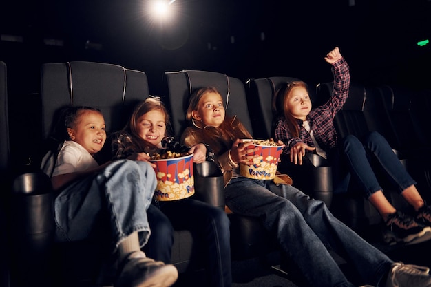 Sitting on the black seats Group of kids sitting in cinema and watching movie together