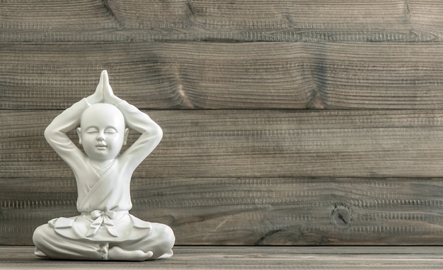 Foto buddha seduto. statua del monaco bianco su fondo di legno. meditazione. rilassante. immagine tonica in stile retrò