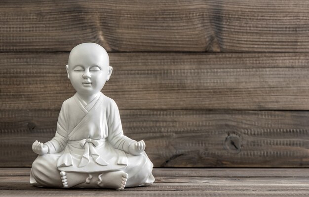 Sitting buddha. White statue on wooden background. Relaxing concept