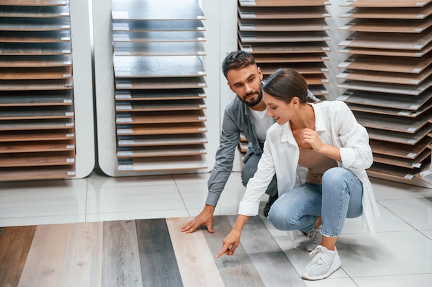 Photo sitting and choosing parquet woman and man is in the store of goods for the home