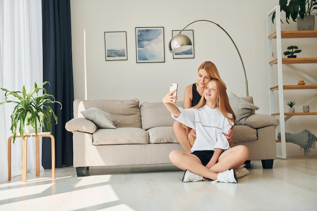 Sitting on the floor Female teenager with her mother is at home at daytime