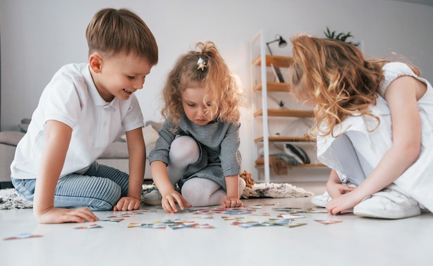 sitting on the floor and playing game group of children is together at home at daytime