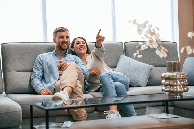 Sitting on the grey colored sofa Couple choosing the bed in the store