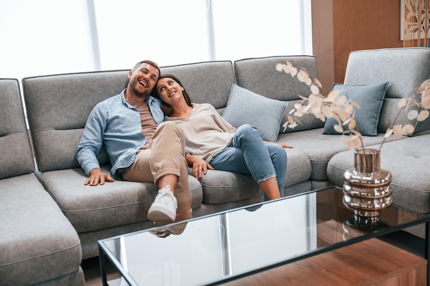 Sitting on the grey colored sofa Couple choosing the bed in the store