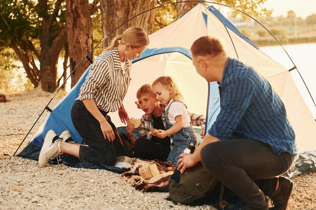 Sitting on the ground Family of mother father and kids is on the camping