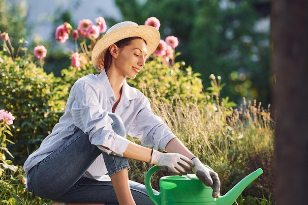 Sitting on the ground Young cheerful woman is in the garden at daytime