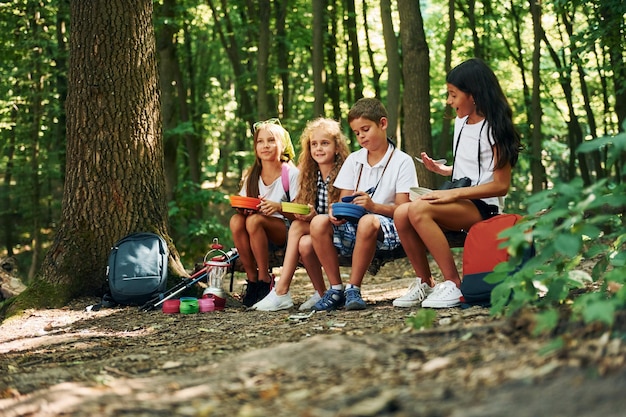 Sitting and having a rest Kids strolling in the forest with travel equipment