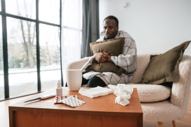 Photo sitting on sofa holding pillow sick black man is at home