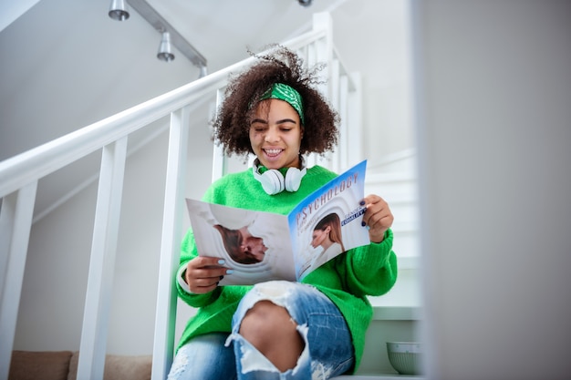 Sitting on stairways. Appealing good-looking lady carrying manual of psychology and reading necessary information