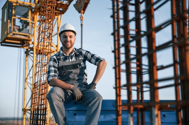 Foto sedersi e fare una pausa l'uomo sta lavorando al cantiere durante il giorno