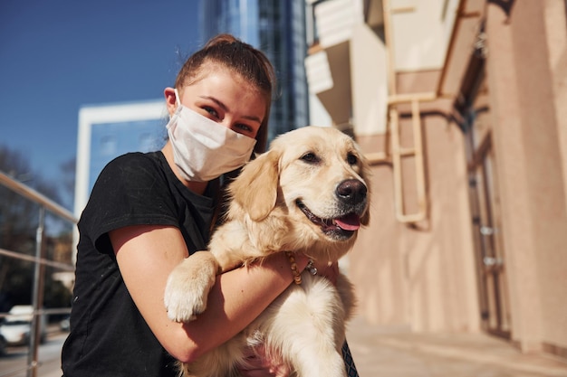 Sitting together Young positive woman in protective mask have a walk outdoors near business building at quarantine time Conception of coronavirus