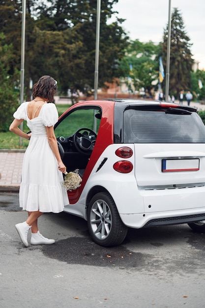 白と赤の車に座っている ドレスを着た花嫁は結婚式が始まる前に屋外にいる