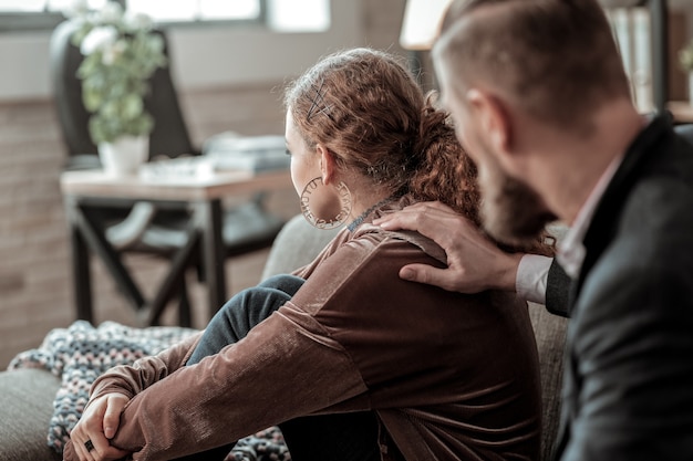 Sitting with back. Curly dark-haired teenage girl sitting with her back to caring concerned father