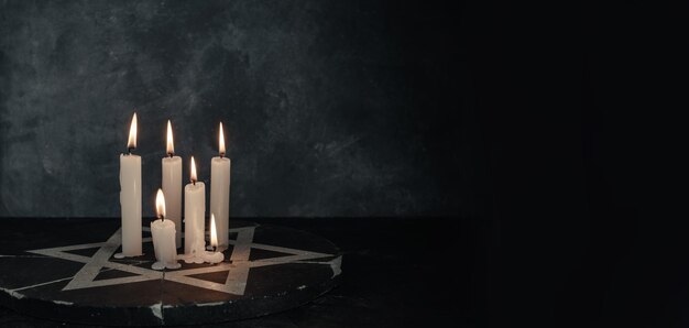 Photo six burning candles and the star of david against on a dark gray background wall