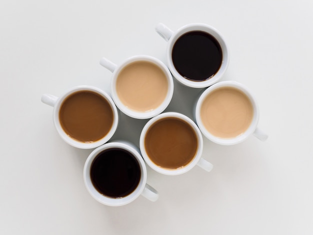 Six cups of coffee of different colors on a white.