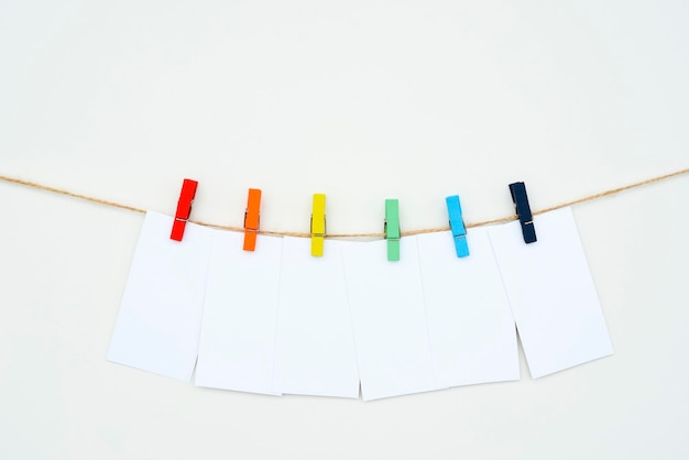 Six empty white cards hang on colour clothespins space for text tag word sixletters mockup