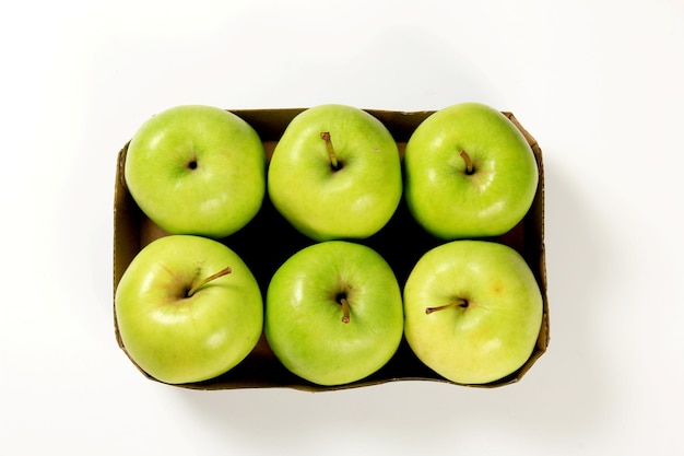 Six green apples in a packing box on a white background