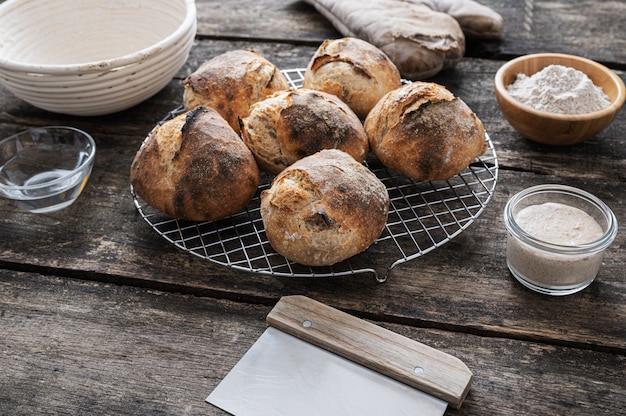 Six home made sourdough bread buns cooling on kitchen rake