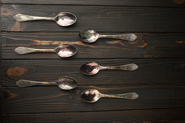 Six old silver spoons on a rustic wooden background