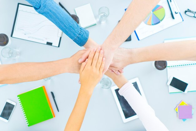 The six students hold hands at the desktop. view from above