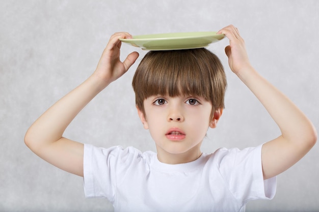 Six years old boy with empty green plate. Free space for a text.