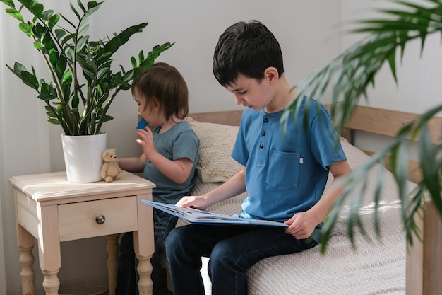 A sixyearold boy is reading a book while sitting on the bed Home schooling Preparation for school