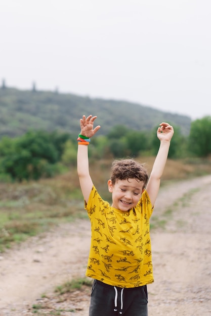 Un ragazzo di sei anni corre in campagna bambino felice che ride e gioca nella giornata estiva