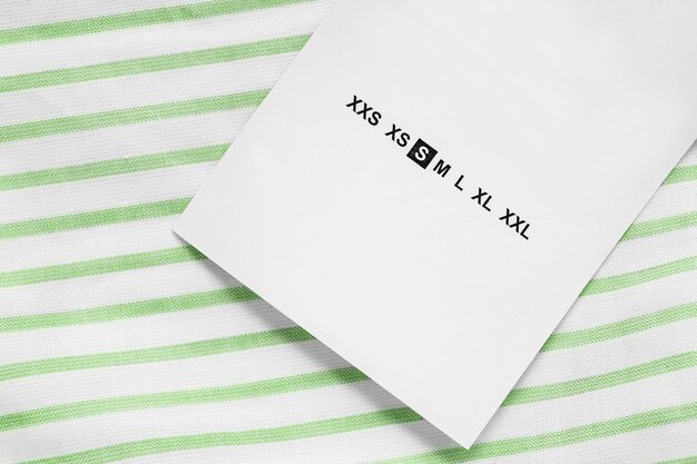 Size S clothes label on white and green cotton fabric closeup