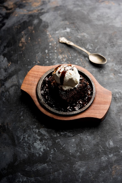 Sizzling chocolate brownie is a sweet dish made using scoop of ice-cream on top served with a generous pouring of melted chocolate. server hot. selective focus