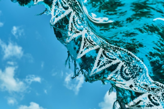 Sjaal ontwikkelt zich sierlijk tegen de lucht zeebries aan de kust pareo close-up wazig niet scherp abstracte achtergrond zee vakantie idee