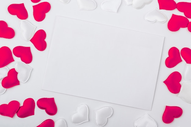 Sjabloon leeg wenskaart en envelop voor de bruiloft. een vel papier tussen rode en witte harten. plat lag, kopieer ruimte voor tekst