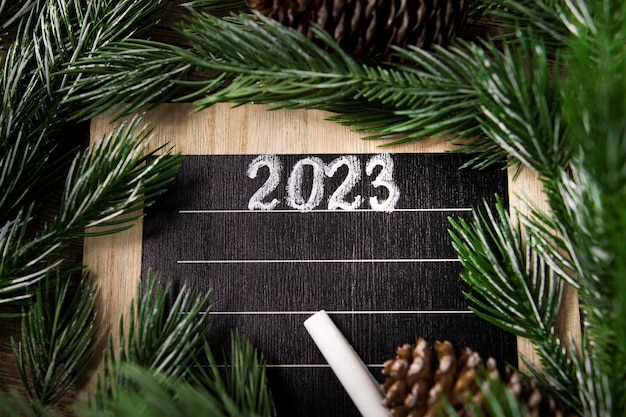 Sjabloon voor het schrijven van doelenplanlijst voor 2023 op een houten achtergrond met een kerstboom