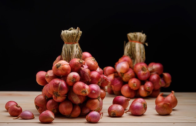 Sjalotuien in een groep op houten tafel op de zwarte achtergrond Sjalotten zijn Thais eten en Thaise kruidenkruiden die sjalot vers koken