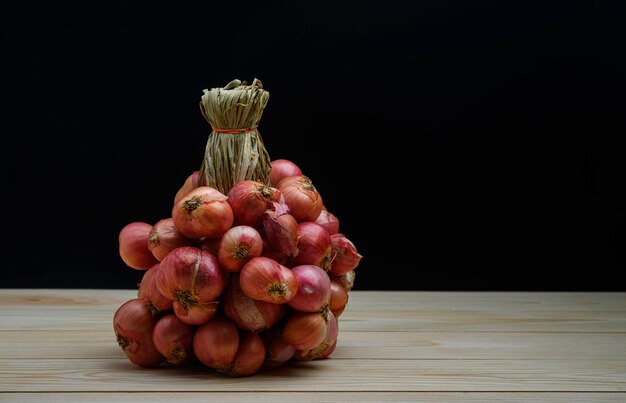 Sjalotuien in een groep op houten tafel op de zwarte achtergrond Sjalotten zijn Thais eten en Thaise kruidenkruiden die sjalot vers koken