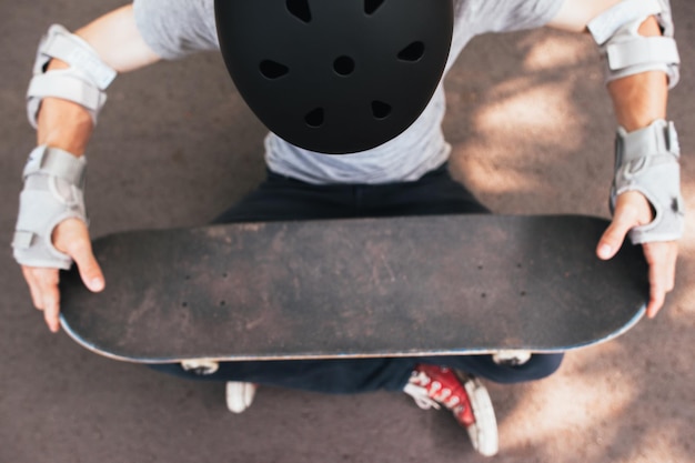 Protezione casco, gomito e guanti da skateboard su skateboarder irriconoscibile. sfida e allenamento di sport estremi, motivazione per vincere in competizione