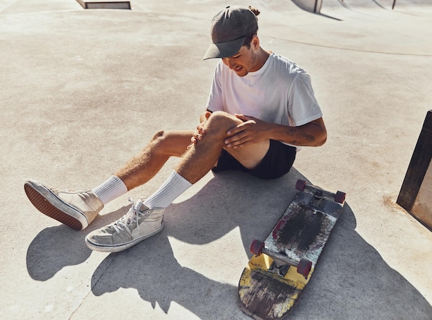 Skateboard knie en blessure met een sportman die zijn beengewricht vasthoudt van pijn na een val of ongeval buiten Fitness skatepark en oefenen met een mannelijke atleet die pijn lijdt tijdens het skaten