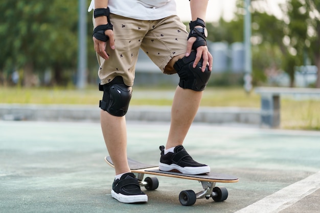Защитное снаряжение и накладки для скейтборда. Азиатский мужчина со скейтбордом вокруг города