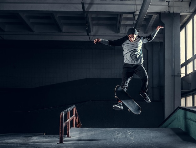 Skateboarder jumping high on mini ramp at skate park indoor.