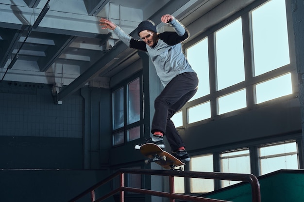 Foto skateboarder che esegue un trucco sulla mini rampa allo skate park al coperto.