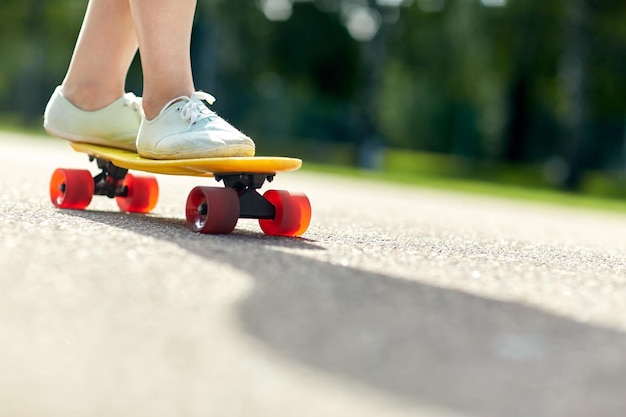 スケート ボード、レジャー、極端なスポーツ、人々 の概念 - 道路で短いモダンなクルーザー スケート ボードに乗って 10 代の少女の足のクローズ アップ
