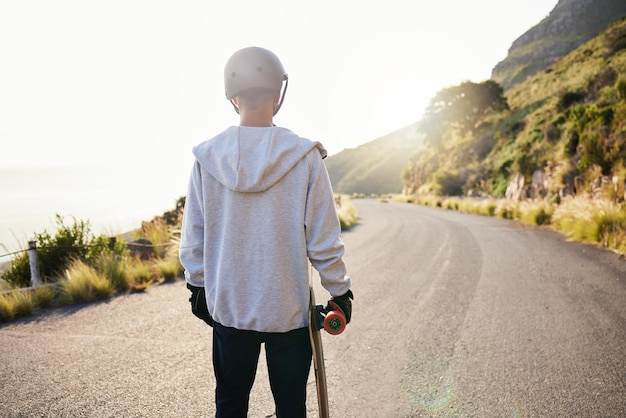 Skateboardweg en atleet doen trainingsoefening en fitness op een heuvel Zon man rug en zomersport van een jongere klaar voor evenwicht en vrijheid van extreme sporten buiten in de zon