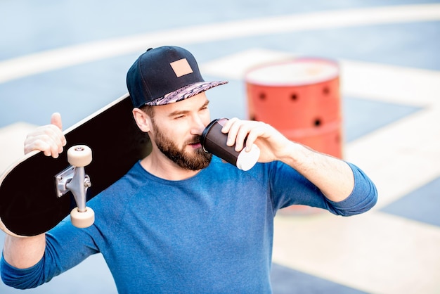 Skateman heeft een koffiepauze terwijl hij buiten op de speelplaats staat