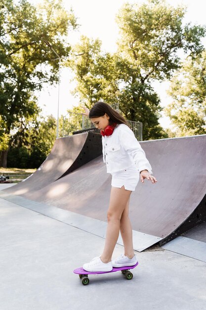 Skater child girl ride on penny board on skate sport ramp at sunset Sports equipment for kids Active teenager with pennyboard on skate park playground