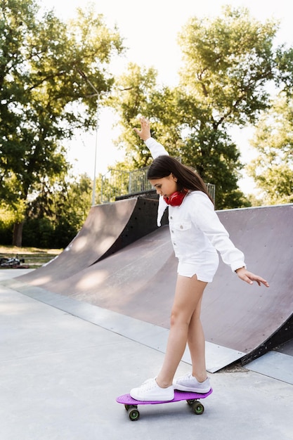 Skater child girl ride on penny board on skate sport ramp at sunset Sports equipment for kids Active teenager with pennyboard on skate park playground