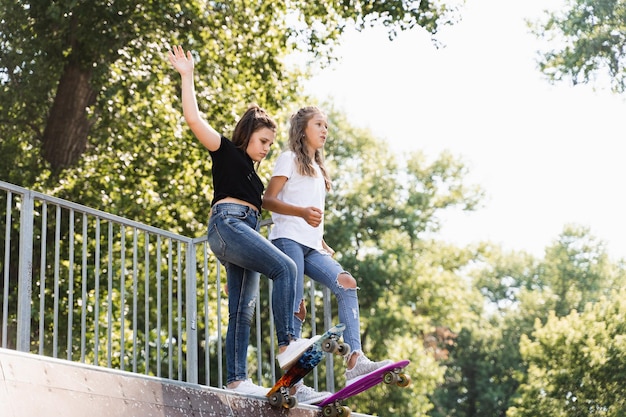 Skater children girls reade to ride on penny board on skate sport ramp at sunset together Sports equipment for kids Active teenager with pennyboard on skate park playground