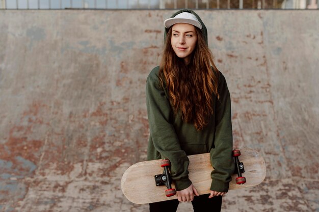 Foto ragazza pattinatrice che tiene il suo skateboard davanti a lei