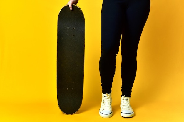 Skater meisje benen dragen witte sneakers op gele achtergrond