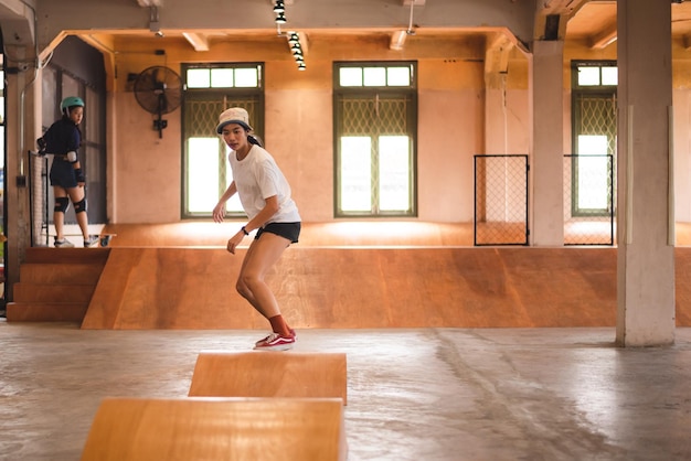 Skater vrouw persoon skateboard spelen in sport sportschool jonge Aziatische vrouw zijn blij en leuk met skateboarden levensstijl in stad tiener hipster vrouwelijke trendy mode