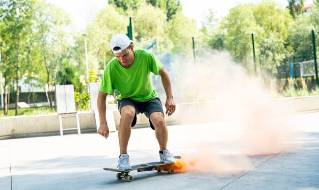 Skaters with colored smoke bombs. Professional skateboarders having fun at the skate park